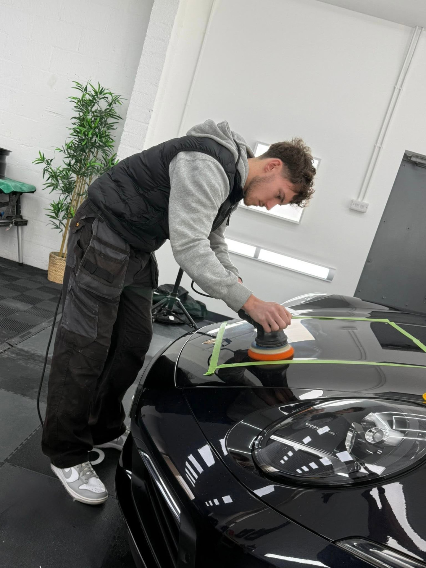 Rhys polishing a black Porsche before coating